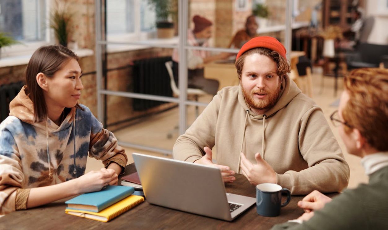 Coworkers engage in a collaborative meeting around a laptop in a modern office setting