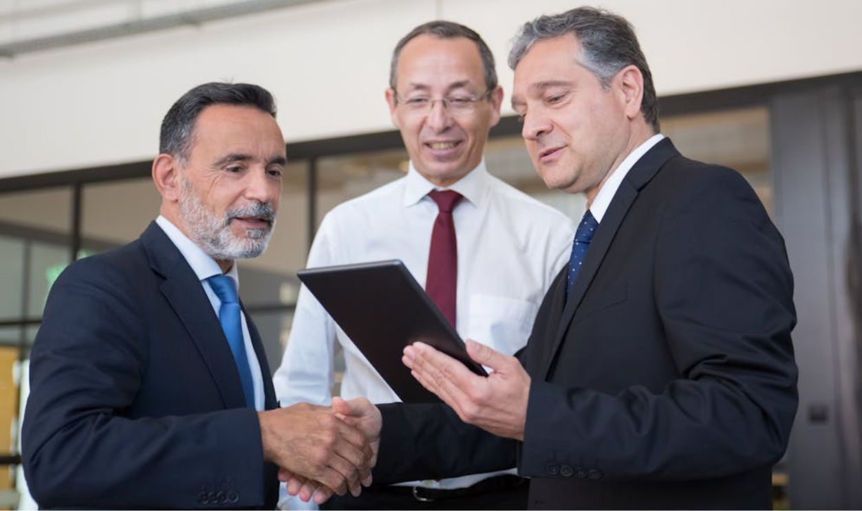 Professional men engaging in teamwork with a digital tablet in a modern office environment