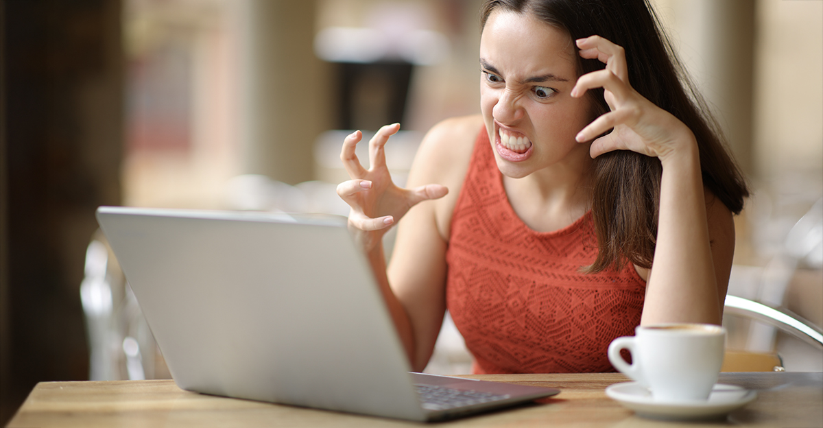 Angry woman with a coffee, looking at her laptop