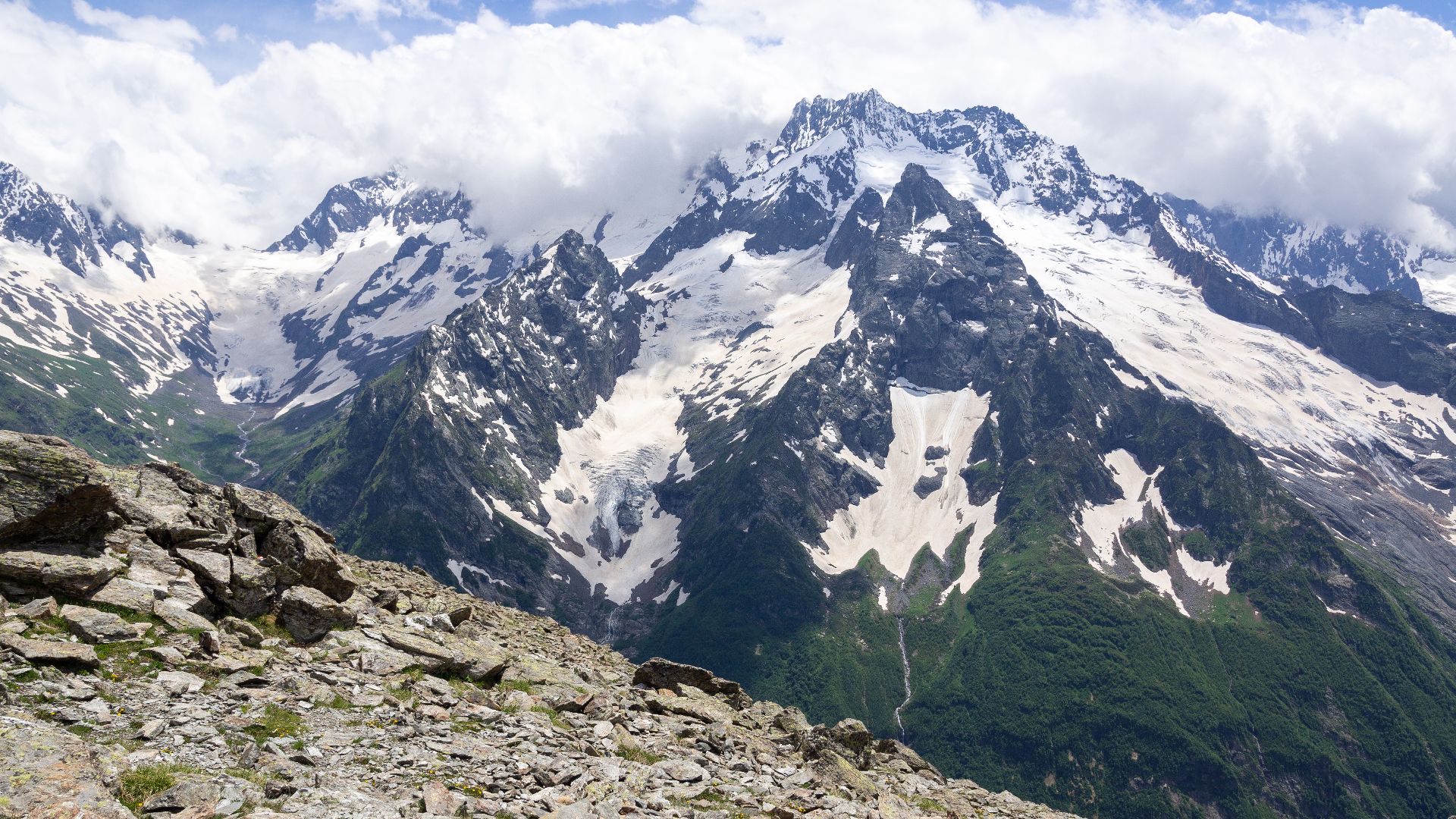 The iconic Dzhuguturlyuchat mountain massif with glacier. The area is mostly below 4000 m. a. s. l. but technically difficult to explore and navigate through rough terrain, snow and glacial activity. Caucasus Mountains. Dombay, Karachay-Cherkessia.