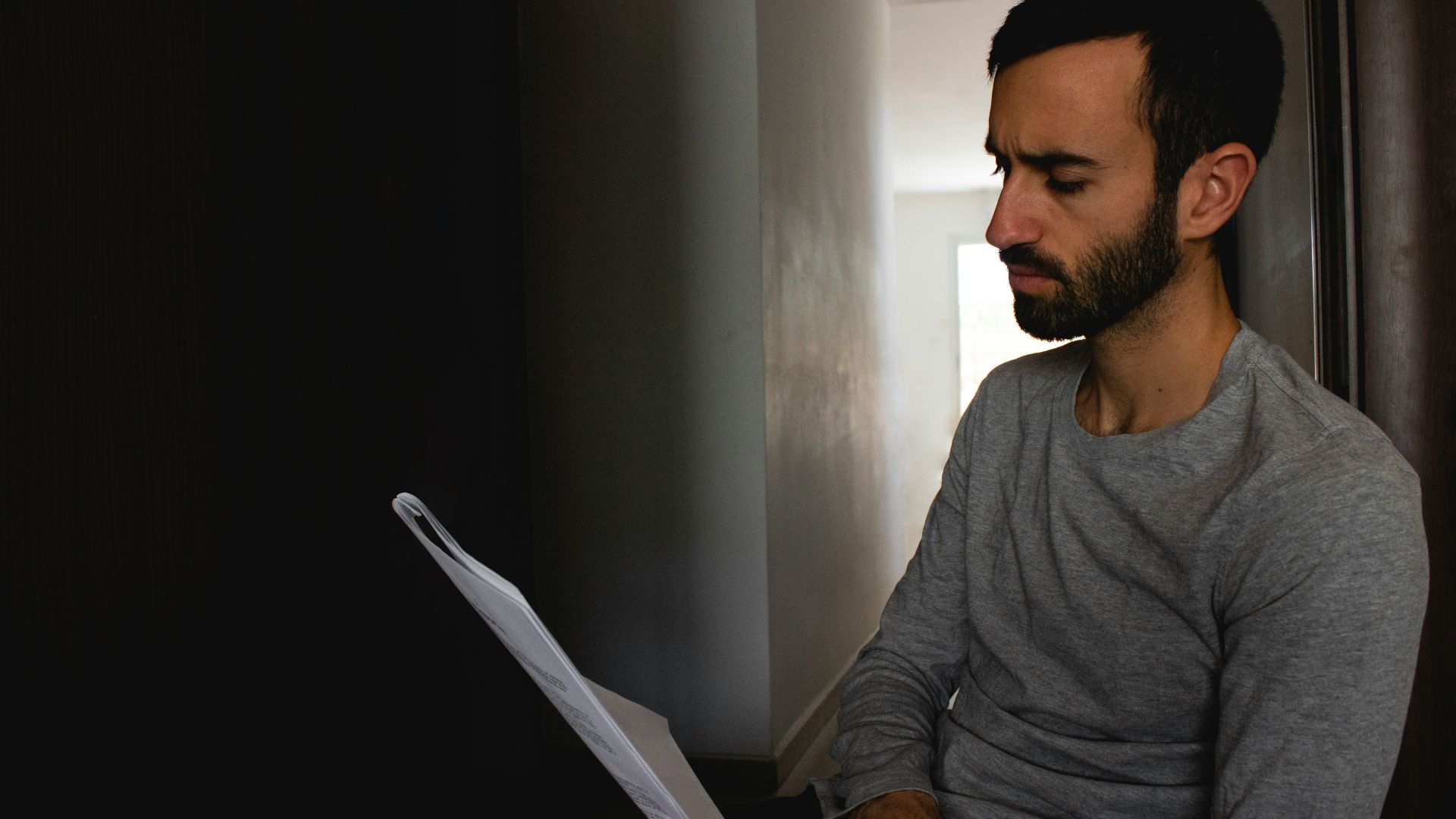 man in gray crew neck shirt holding white printer paper