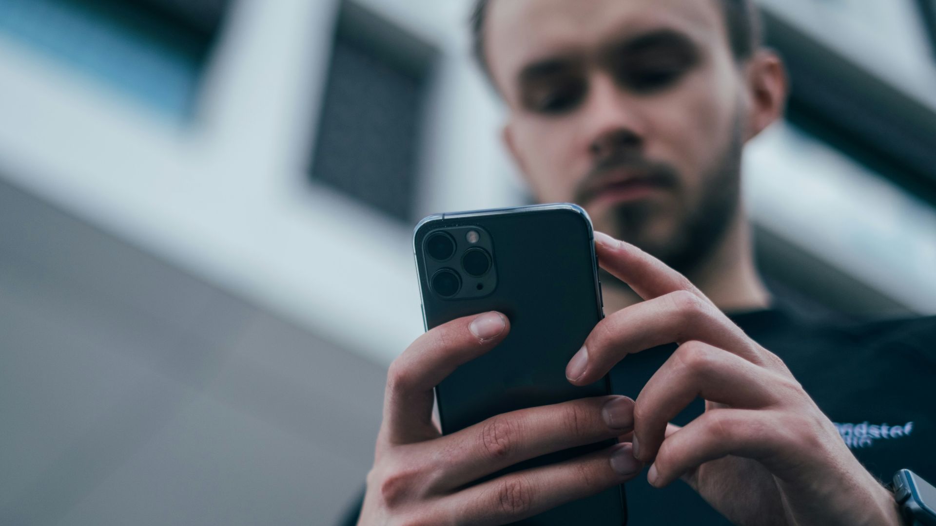 man wearing black sweater using smartphone