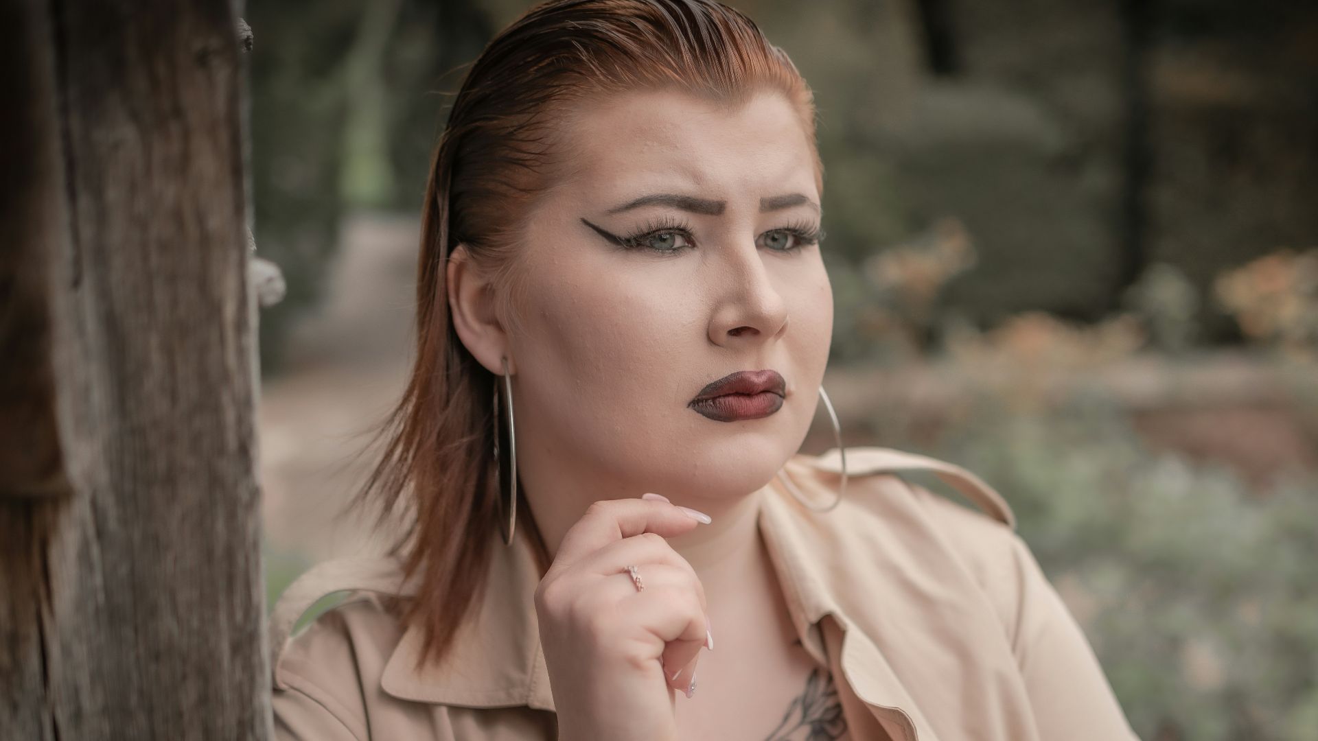a woman with a tattoo on her neck leaning against a wall