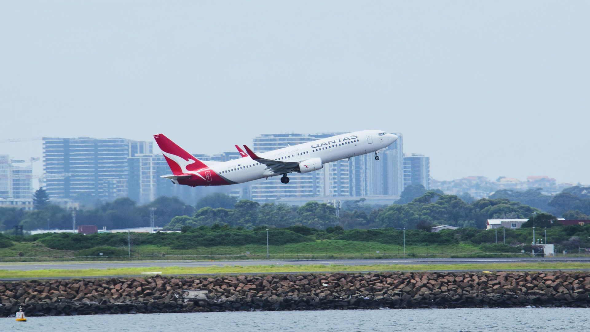 a large jetliner flying over a body of water