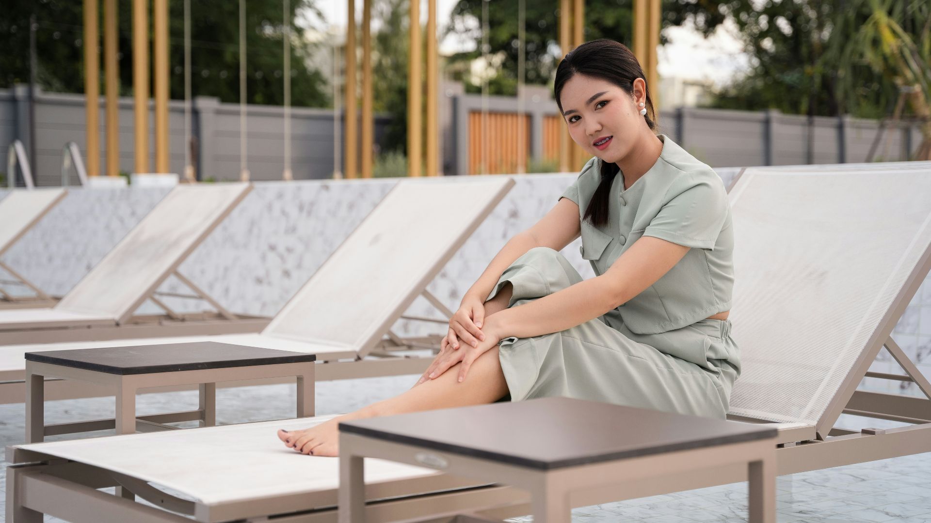 woman in gray dress shirt sitting on brown wooden picnic table during daytime