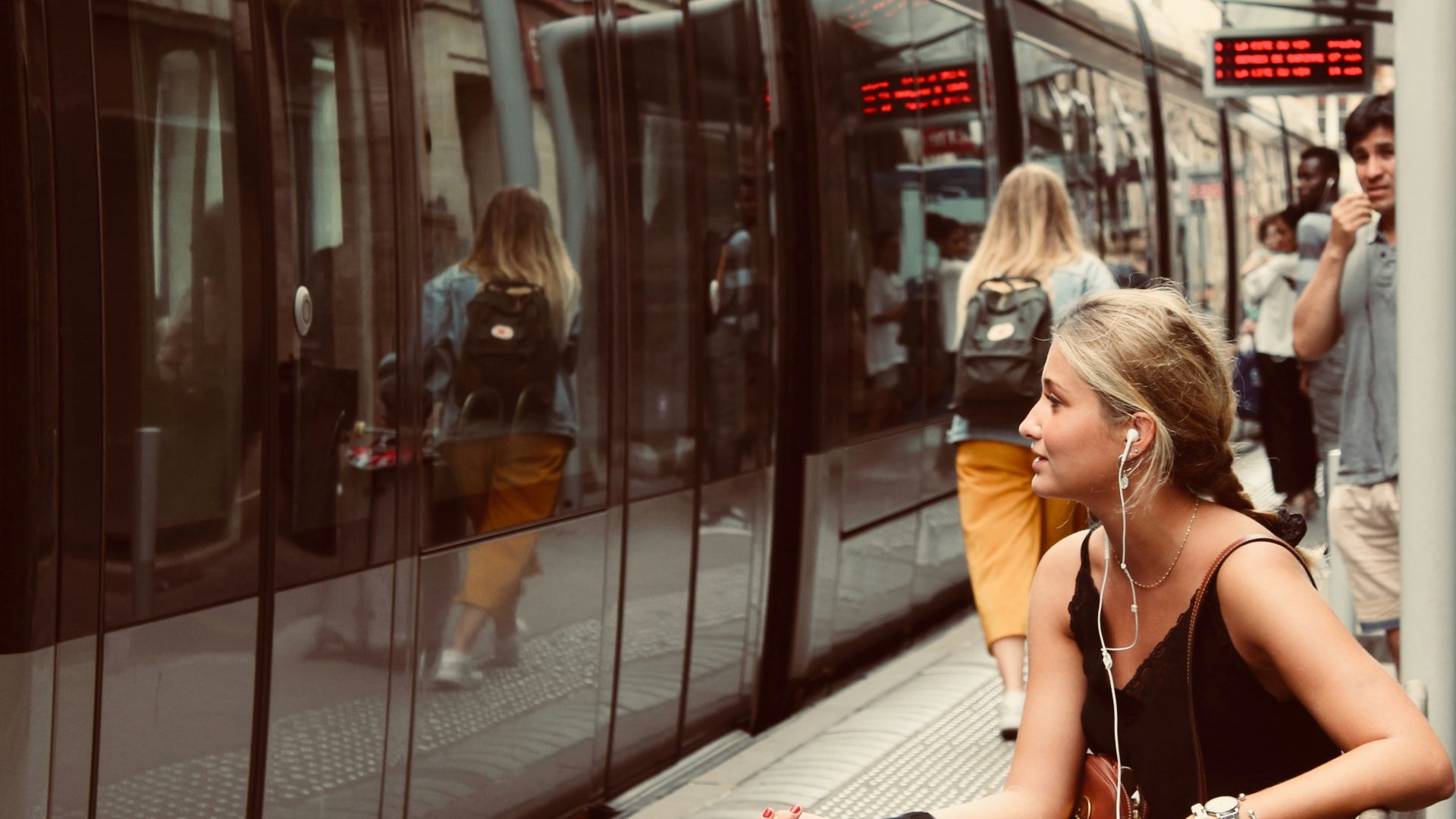 woman sitting on bench in front of train