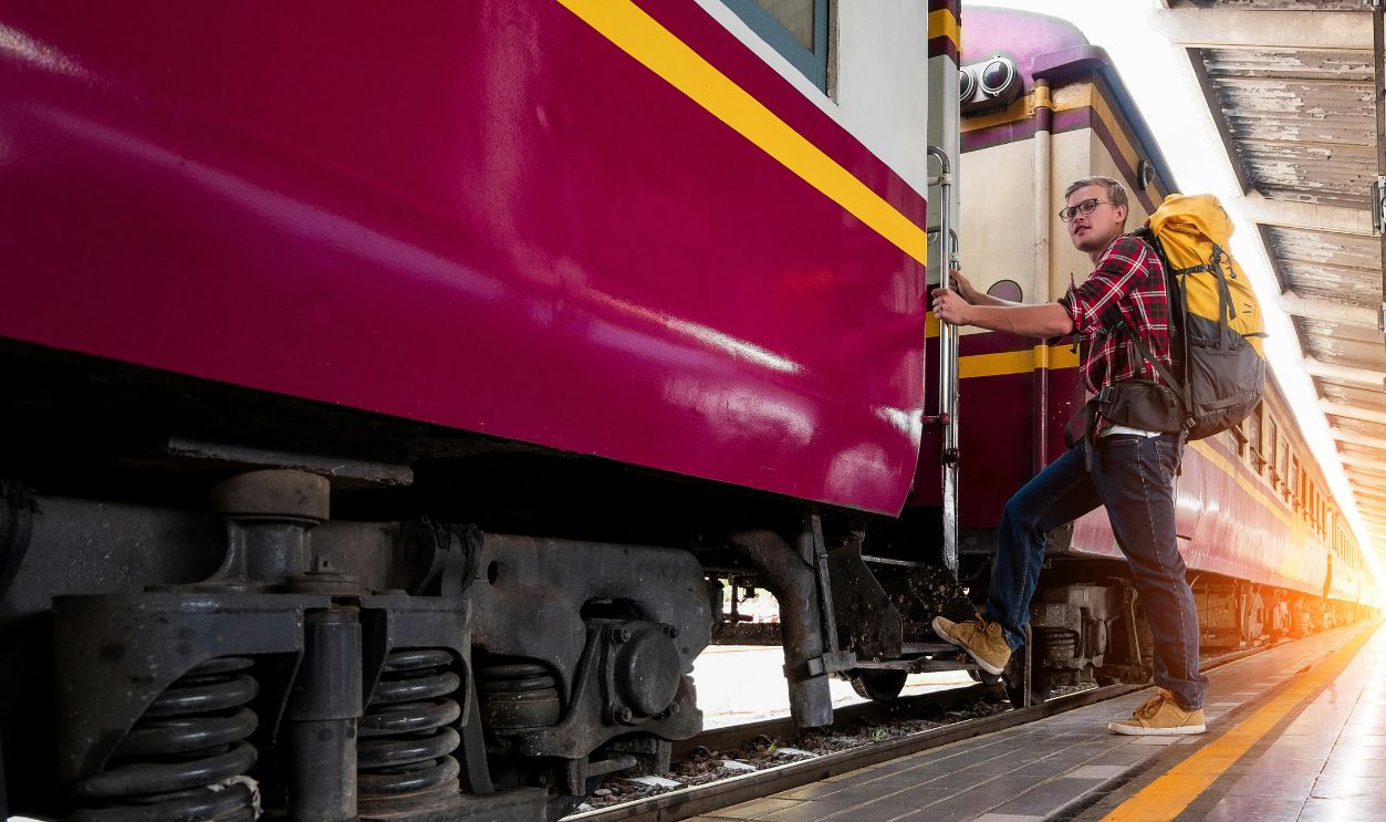 Man with backpack boarding a train at urban railway station 