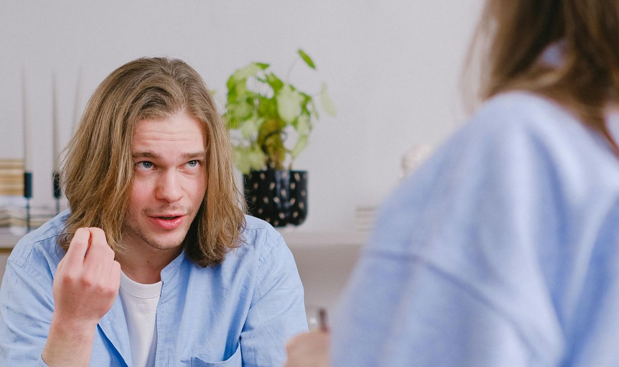 A young man in therapy, gesturing towards therapist in a comfortable setting