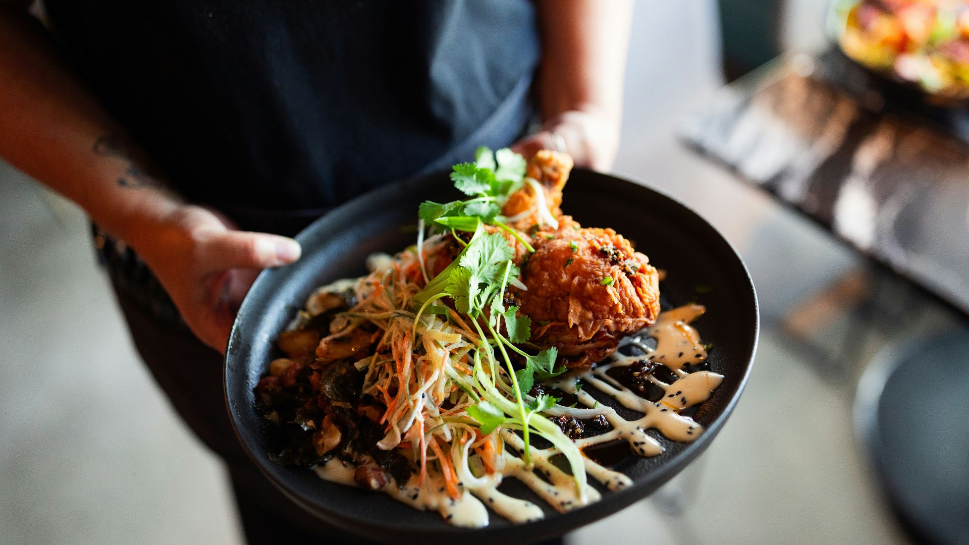 A person holding a plate of food on a table