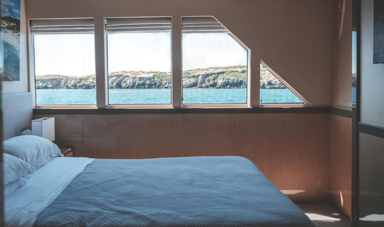 A tranquil yacht cabin interior with ocean views through large windows, perfect for a serene holiday.