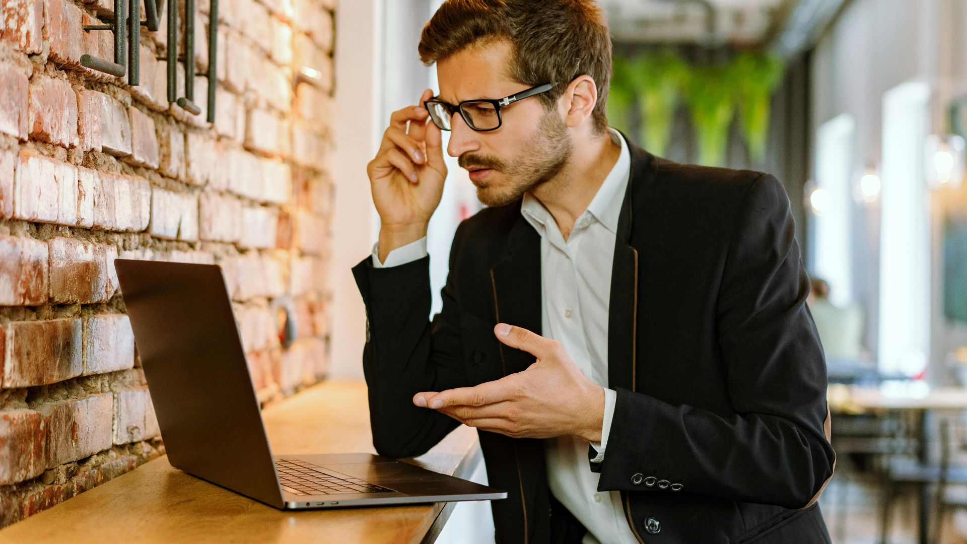 Businessman in a stylish black jacket using a laptop indoors, focused on his work
