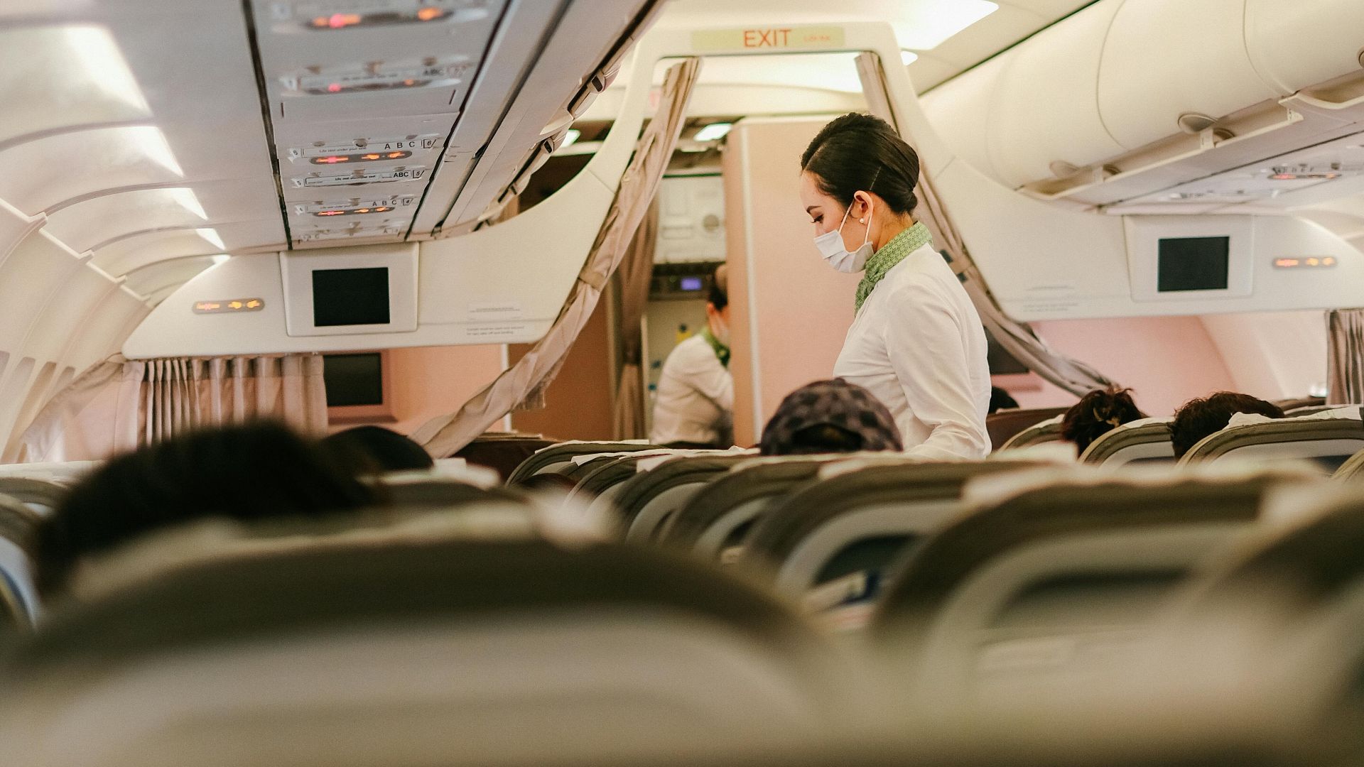 Flight attendant serves passengers in an airplane's cabin interior, focusing on customer service during air travel.
