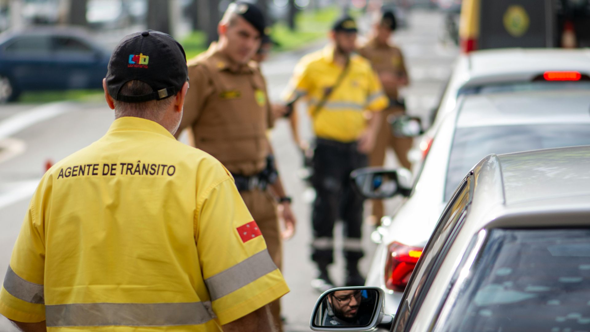 Traffic agent in bright uniform managing vehicles on a busy Londrina street.