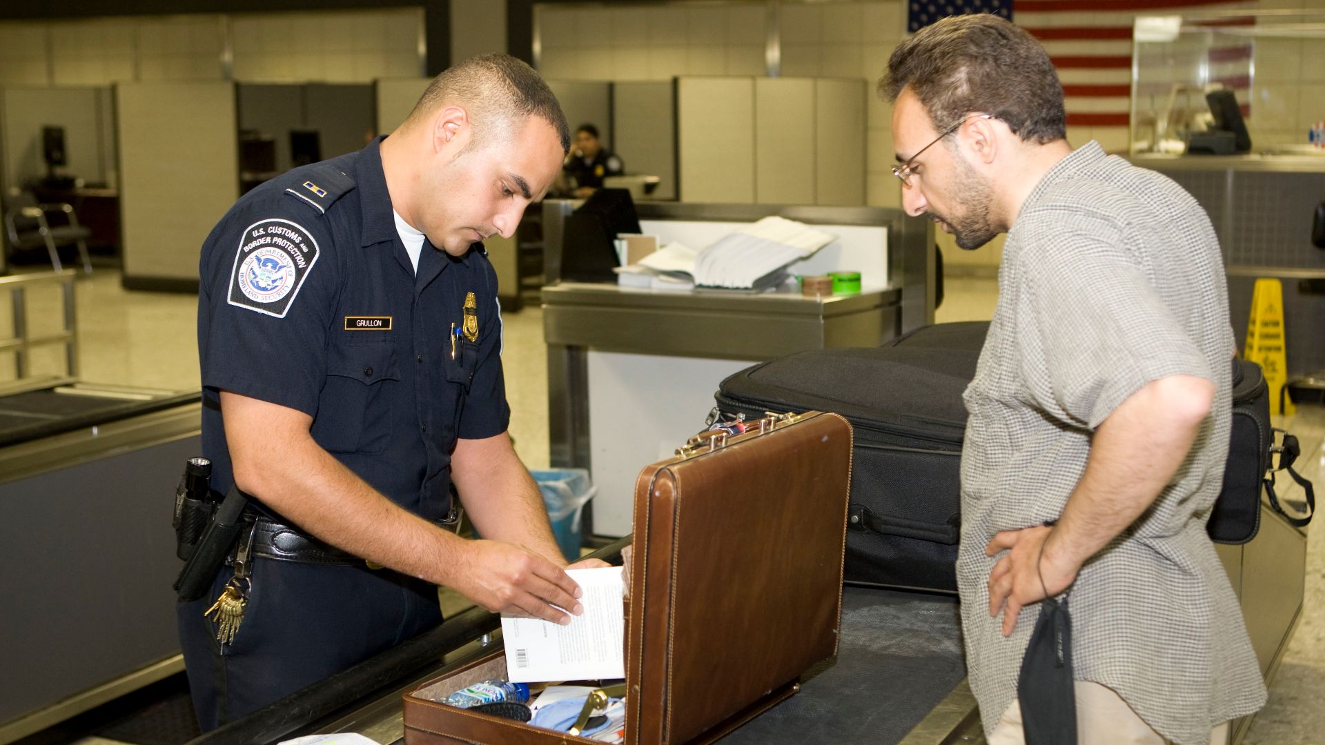 CBP Officer inspects a passengers lugggage at an airport. Photo by James Tourtellotte