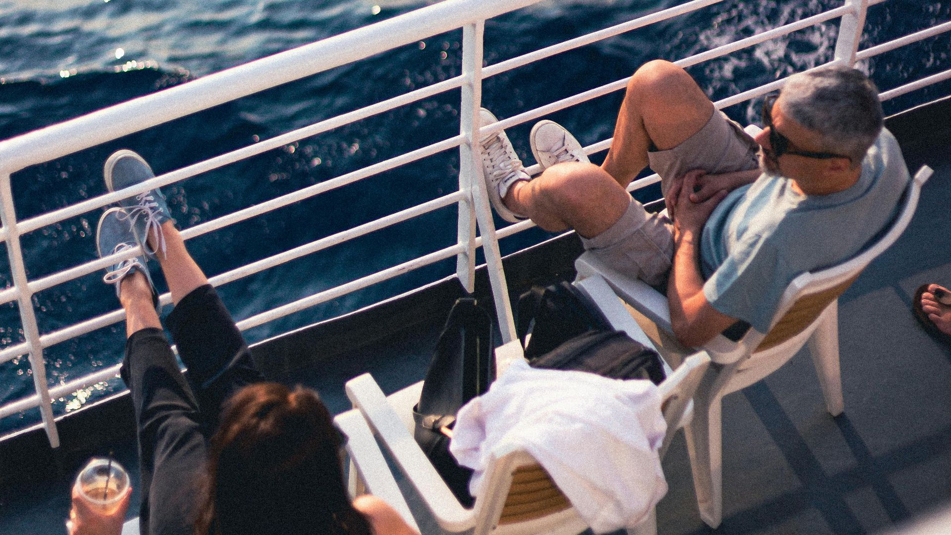 Couple relaxing on a cruise ship deck, enjoying the serene ocean view on a sunny day.