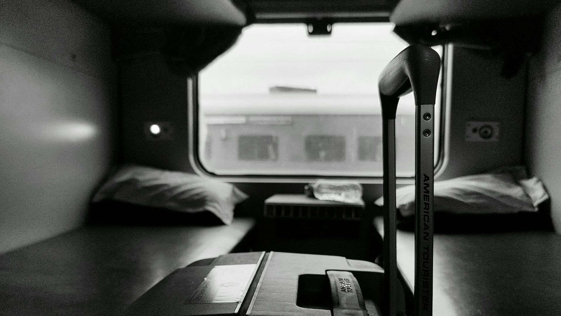 Black and white view of a sleeper train compartment with luggage, evoking travel and adventure.