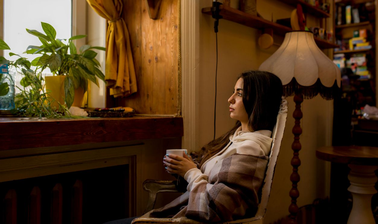 Woman enjoying a peaceful moment by the window with a coffee in a cozy room
