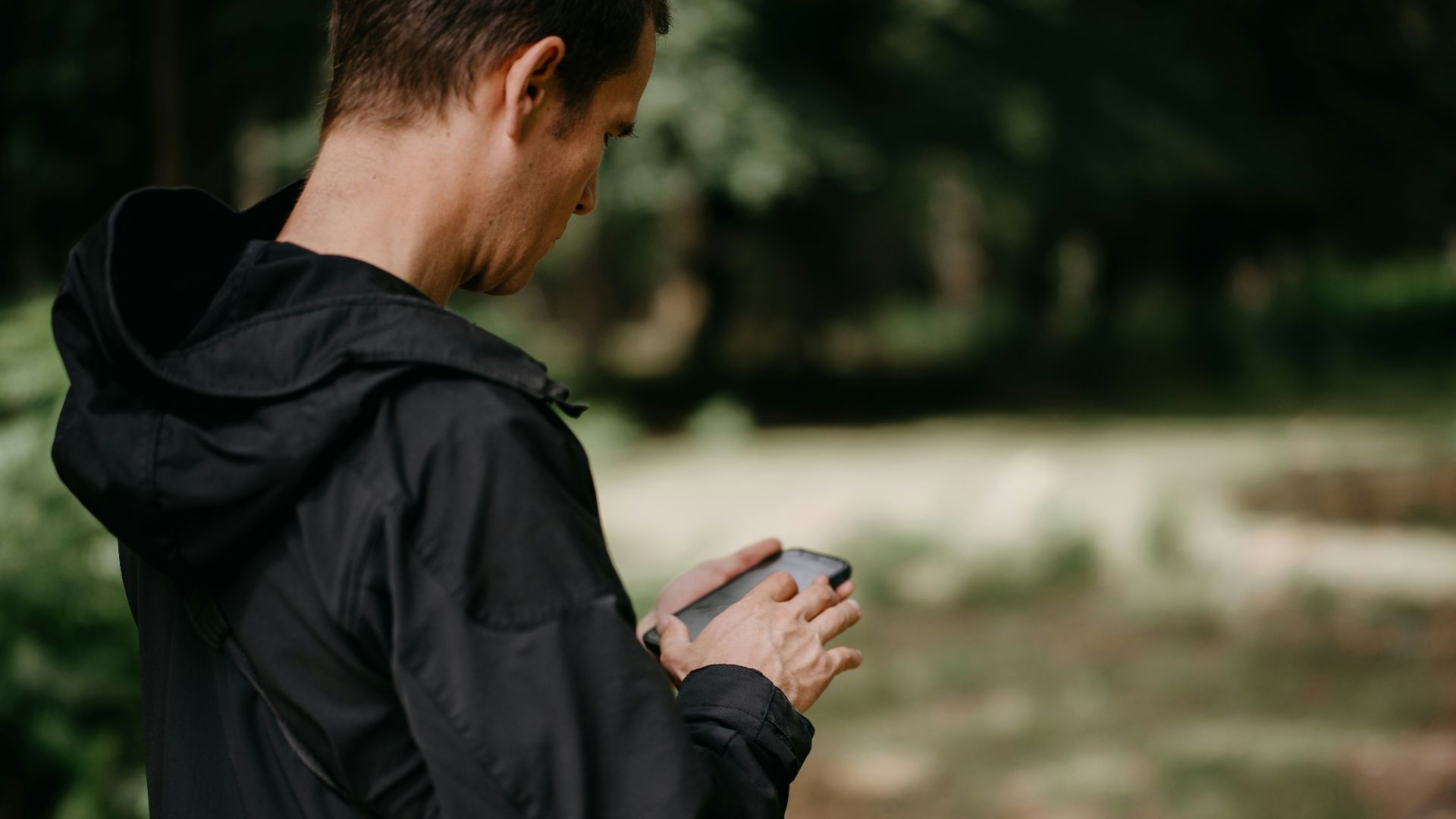 a man standing in the woods looking at his cell phone