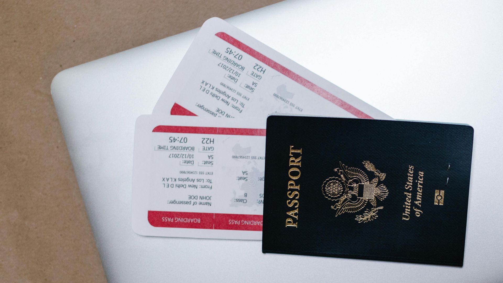 Close-up of a passport and boarding passes on a laptop, symbolizing travel preparation.