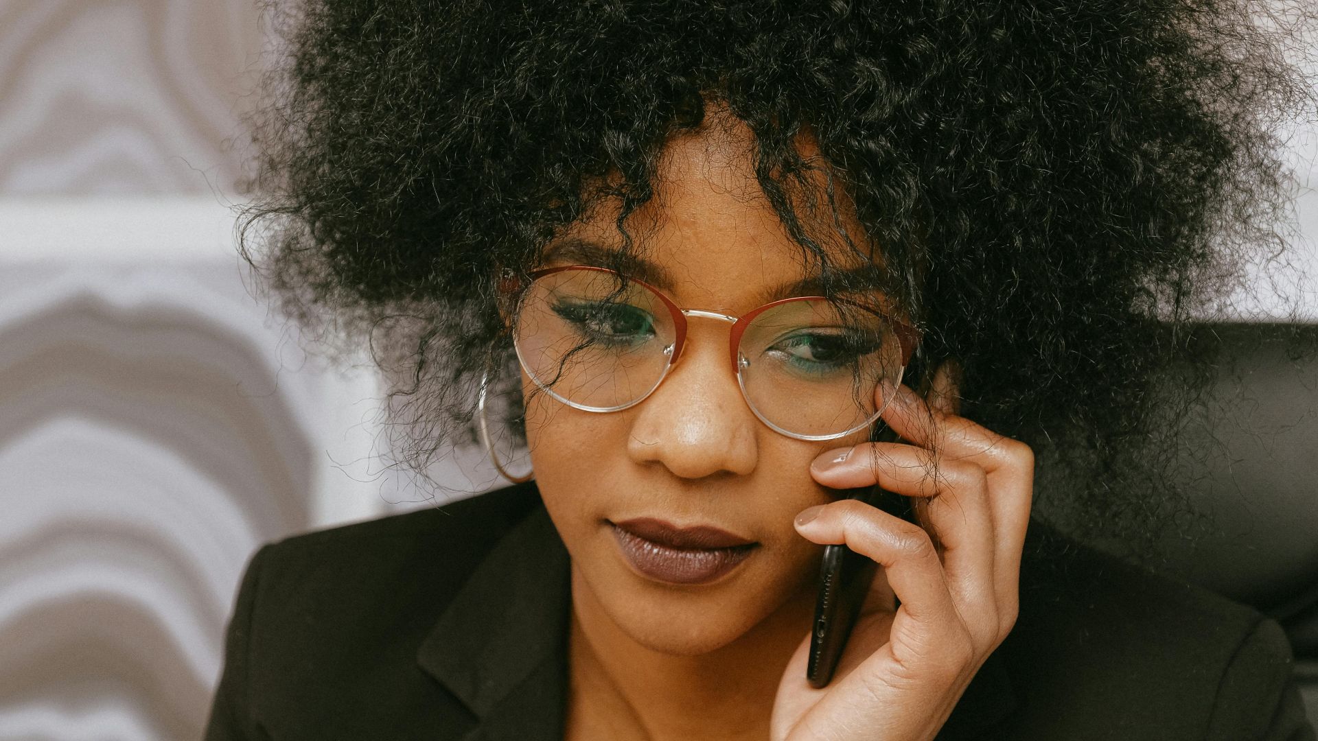African American businesswoman in office, focused on phone call and tasks.