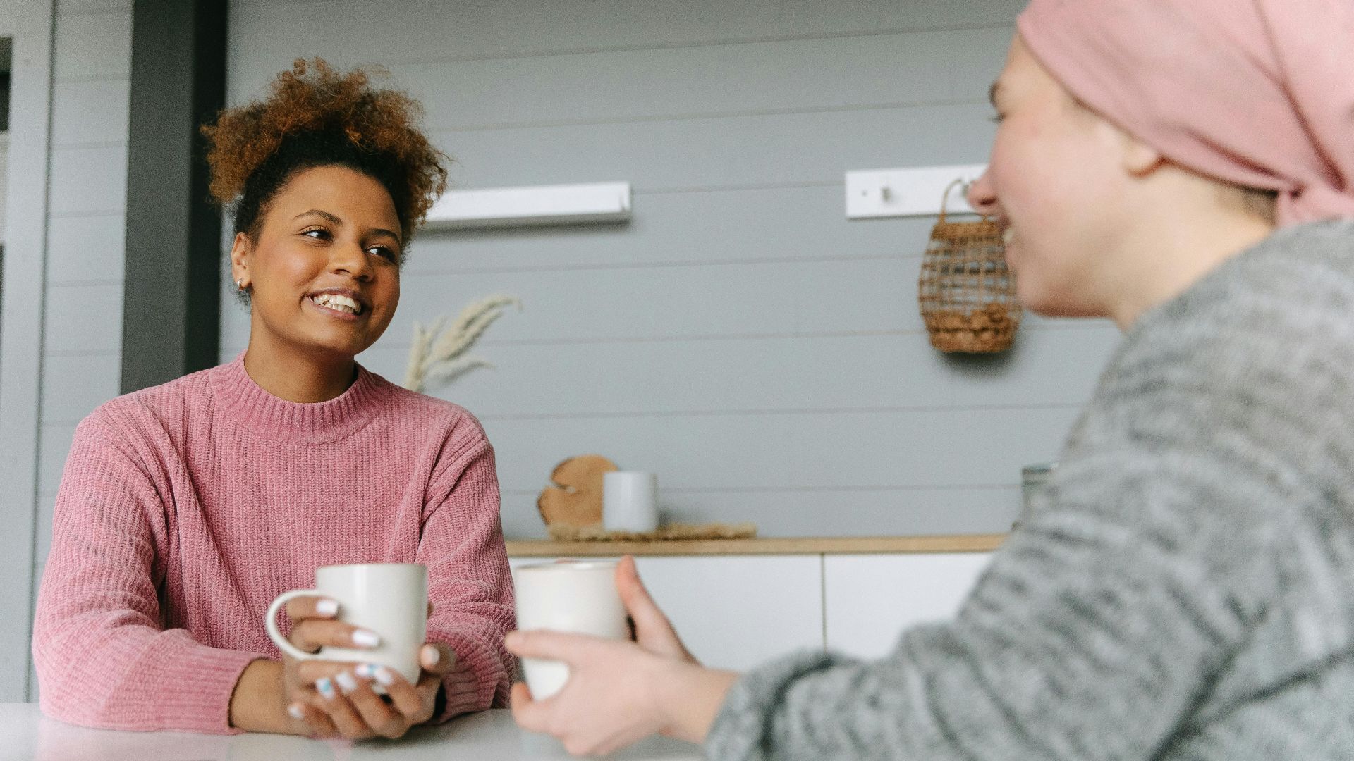 Two women share a joyful coffee moment at home, embodying friendship and warmth.