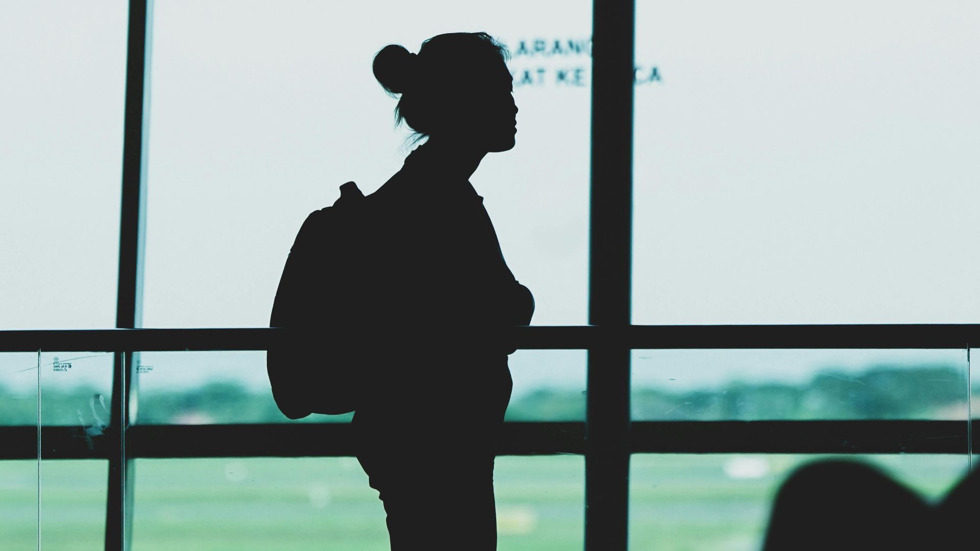 Silhouette of a woman with a backpack standing at Surabaya airport terminal, Indonesia.