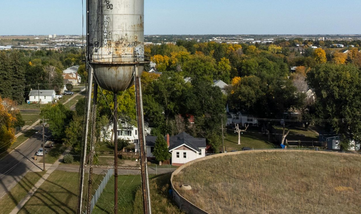 Aerial view of a historic water tower in Minot, ND under a clear blue sky