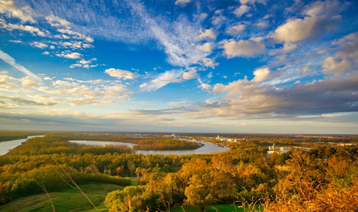 Scenic aerial view of the Mississippi River at sunset, showcasing lush greenery and clear skies.