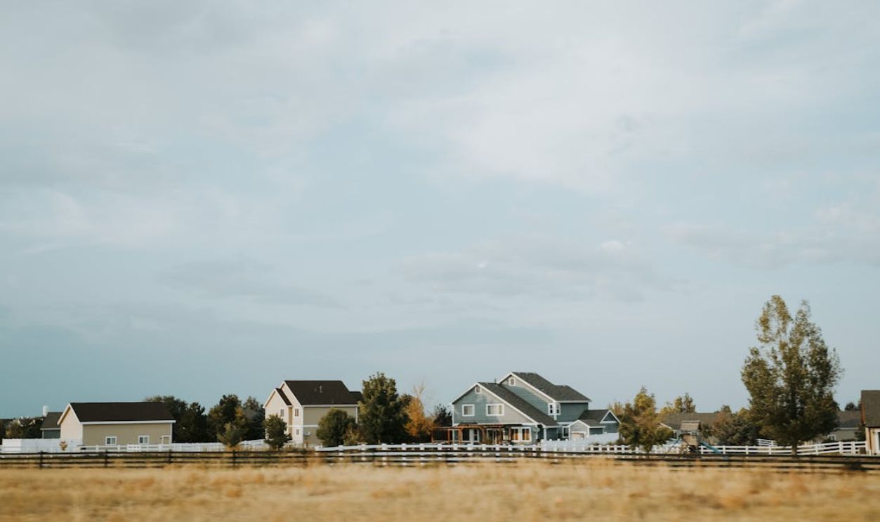 Scenic view of countryside homes with a wooden fence under a wide sky near Denver, Colorado