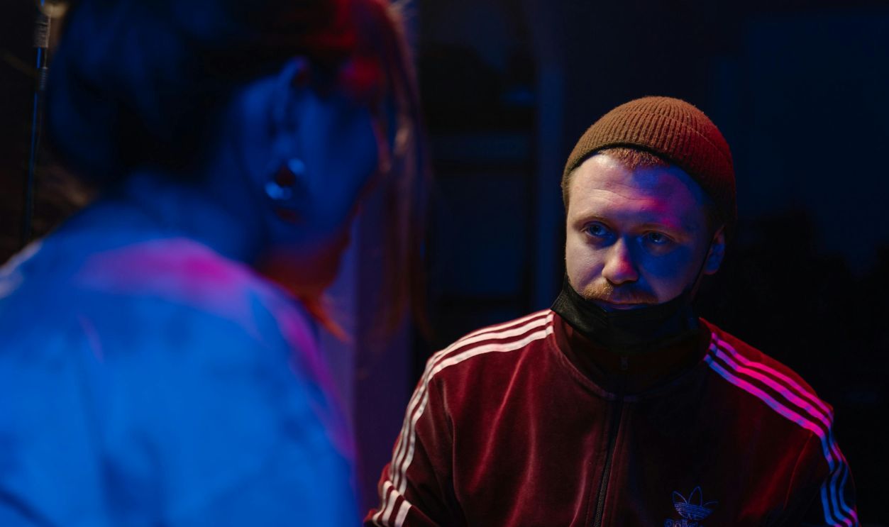 A vibrant neon-lit scene capturing two tattoo artists in a studio, blending modern and artistic styles