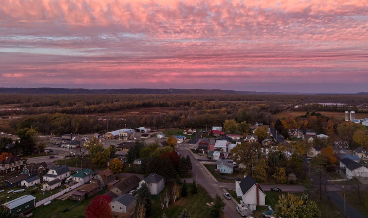 Aerial view of Nelson, Wisconsin showcasing a picturesque sunset with vibrant clouds over a serene village landscape
