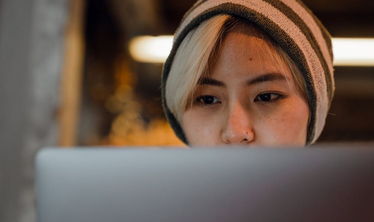 Young woman with beanie concentrating on laptop in cozy cafe setting