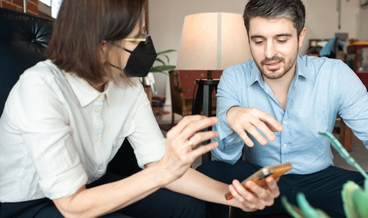 Two professionals engaging in a conversation, reviewing information on a smartphone in a modern office lounge