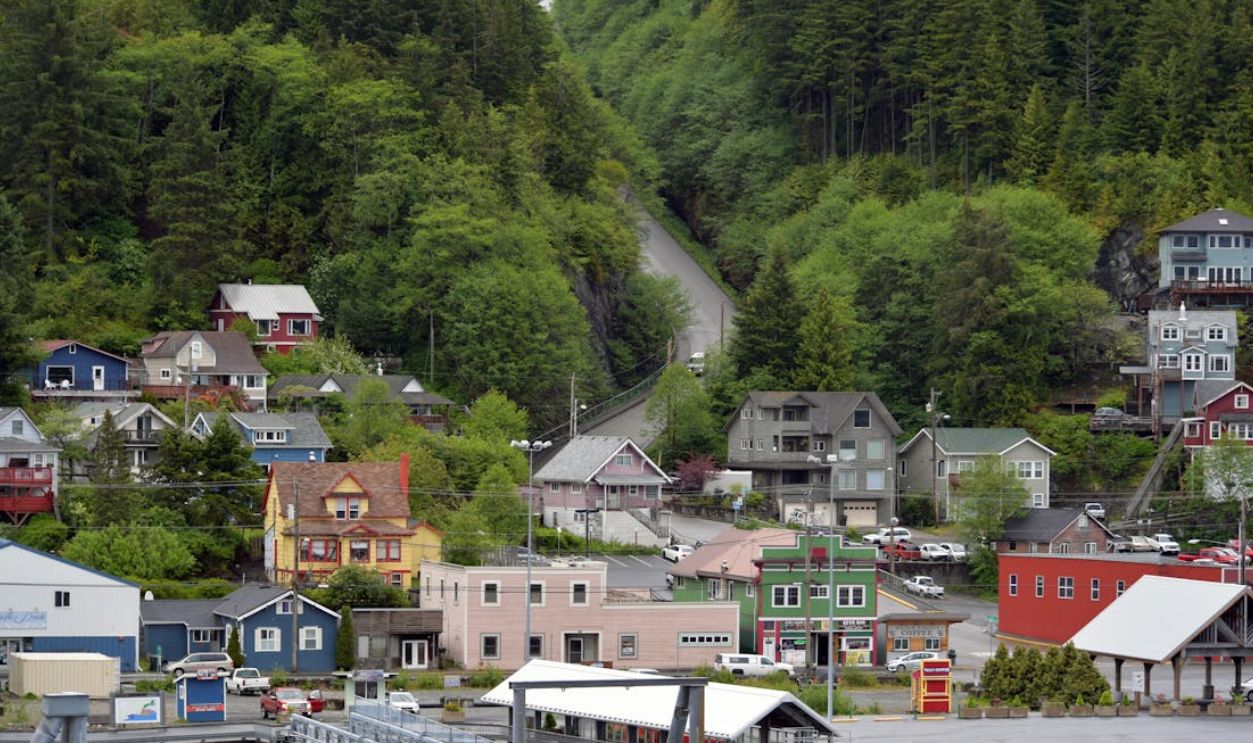 Picturesque small town surrounded by lush green hills and dense forest, showcasing colorful houses and serene scenery