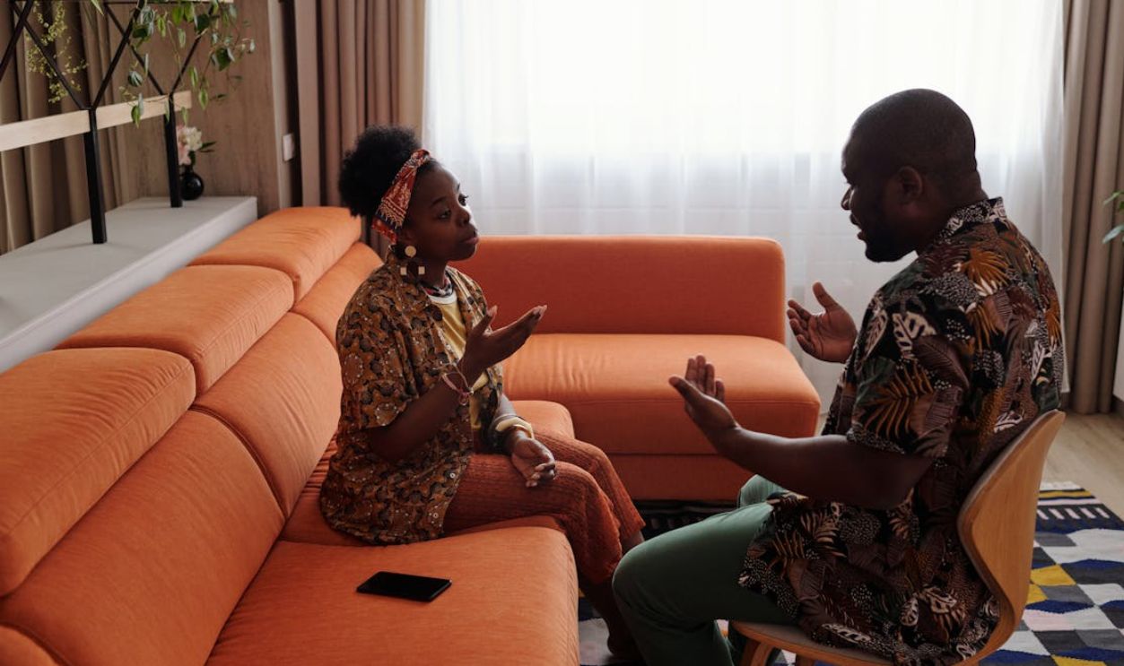 A couple having an emotional discussion on an orange sofa in modern living room