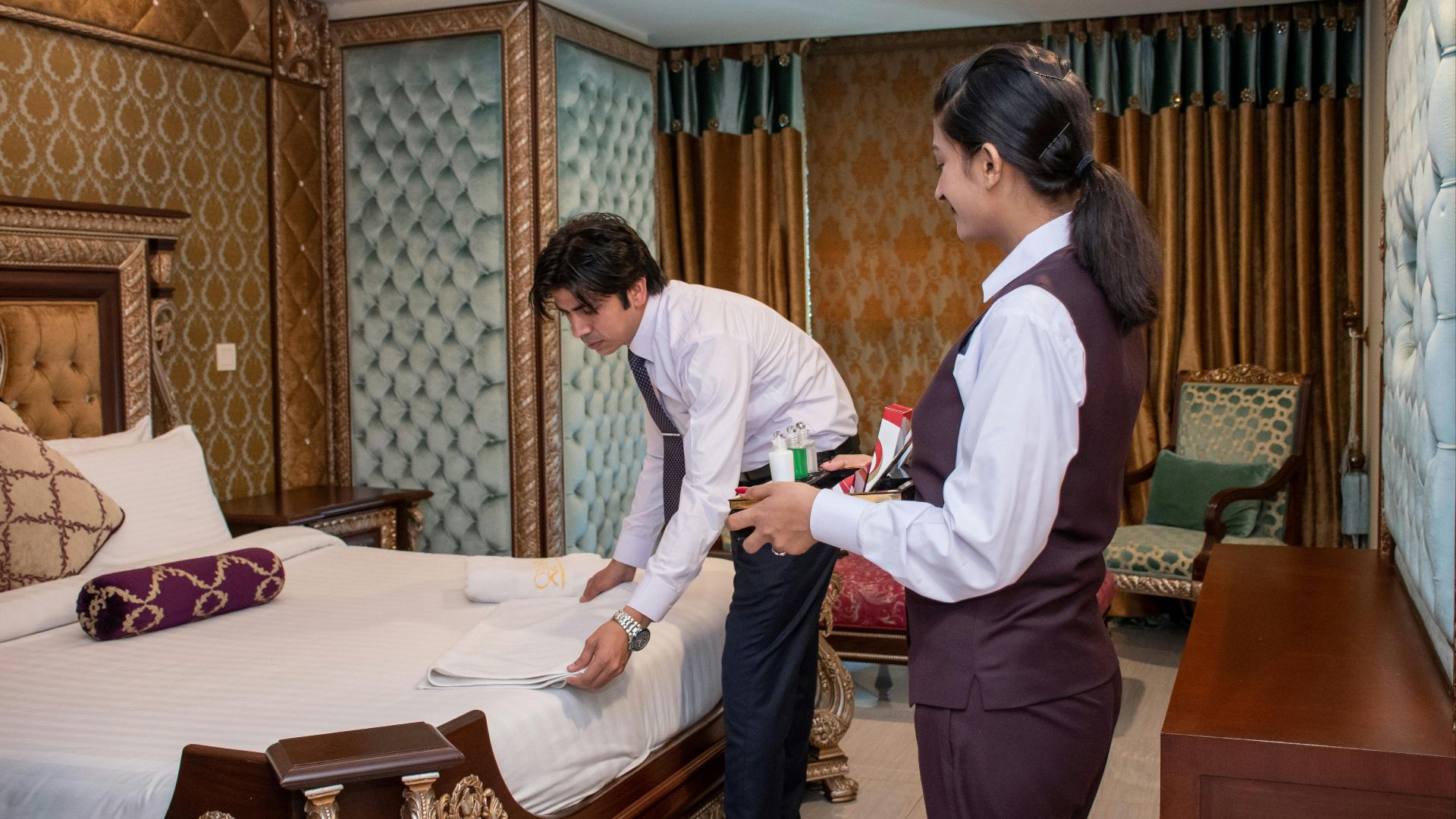 Hotel staff arranging bedding in a luxury room, showcasing service quality in Islamabad.