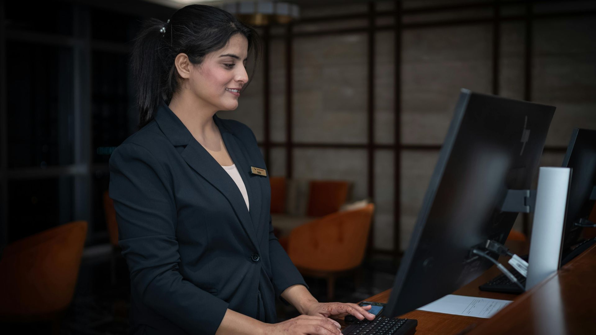A female receptionist working at a hotel front desk in Islamabad, Pakistan.