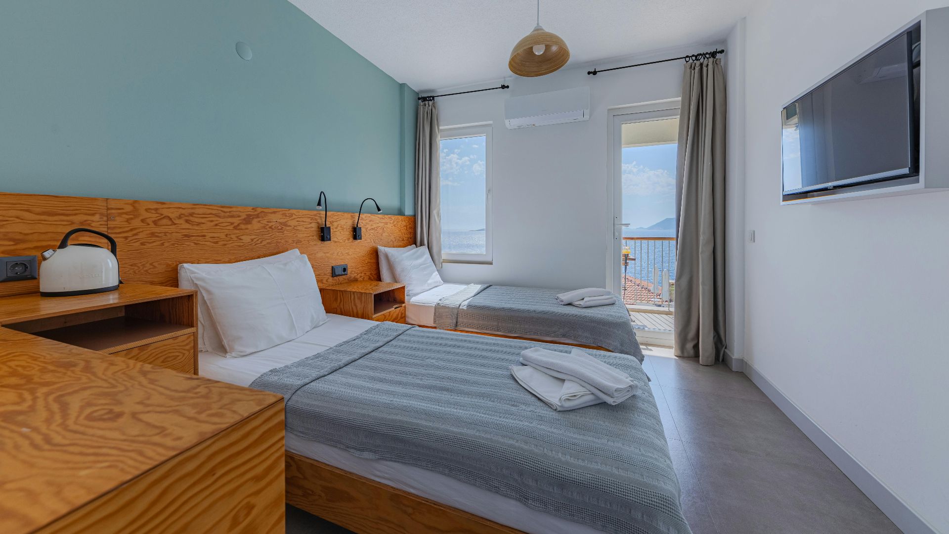 Bright hotel room featuring twin beds, modern decor, and a stunning sea view.