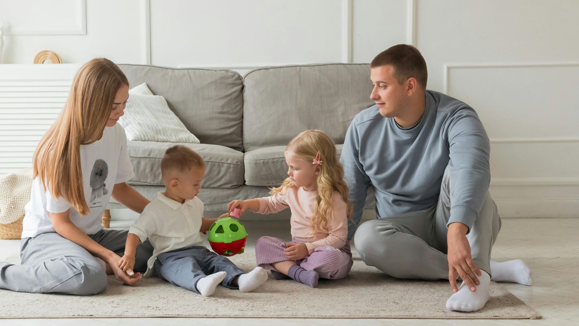 Parents and children enjoying quality time at home, playing with toys in a cozy living room setting.
