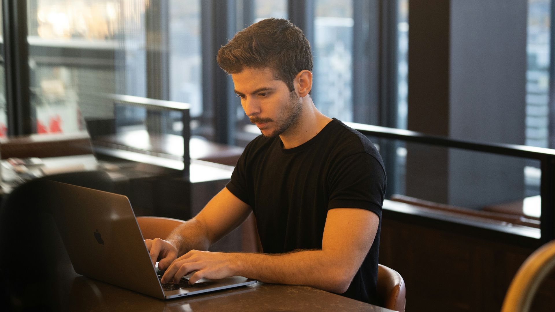 man in black crew neck t-shirt using macbook