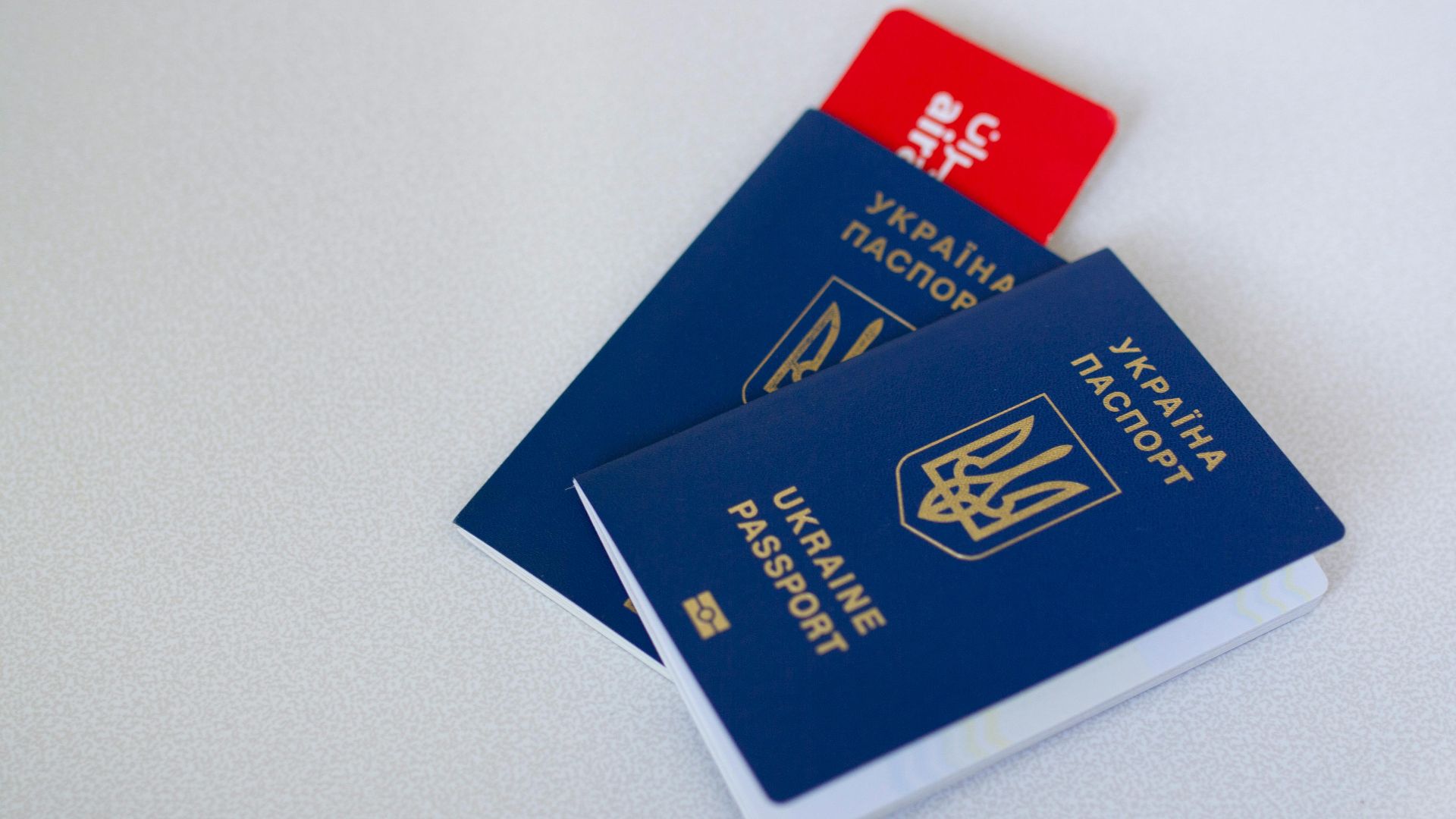 Close-up of Ukrainian passports and travel card on a light surface with ample copy space.