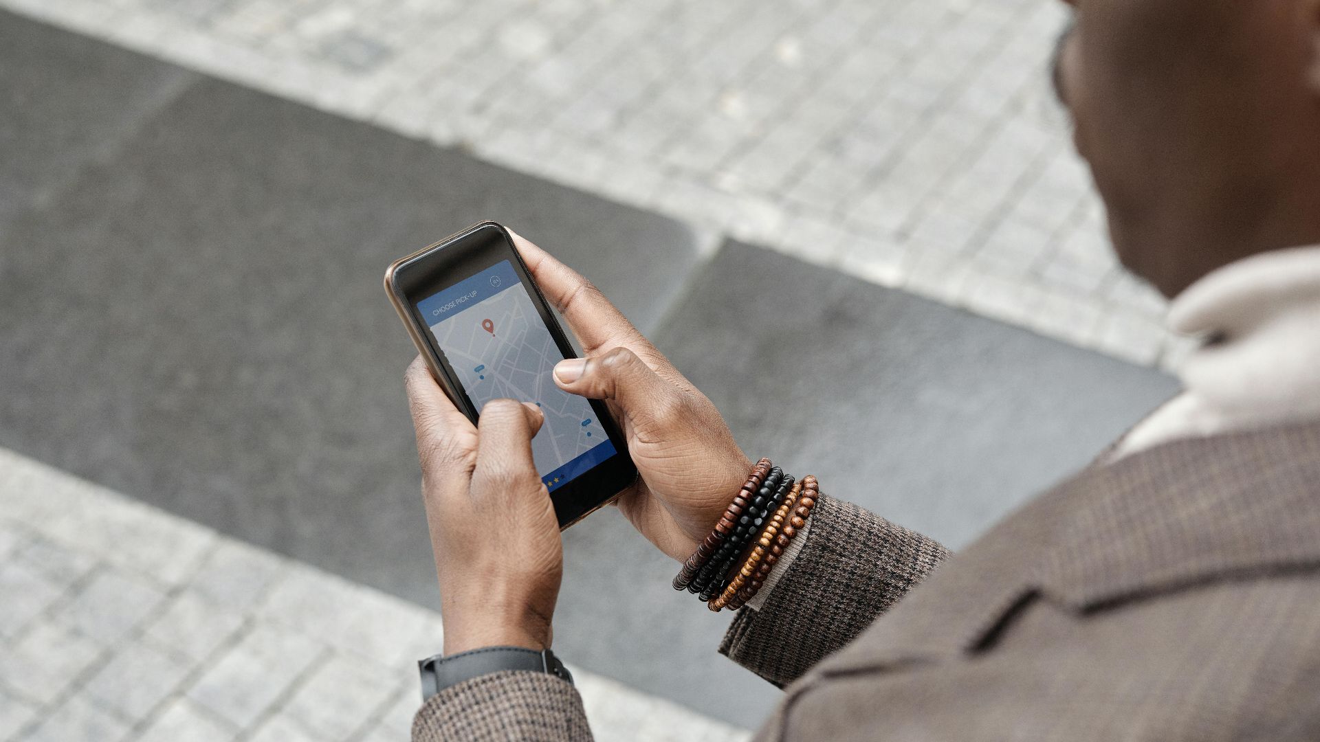 A stylish professional adult using a smartphone with a navigation app on an urban street.