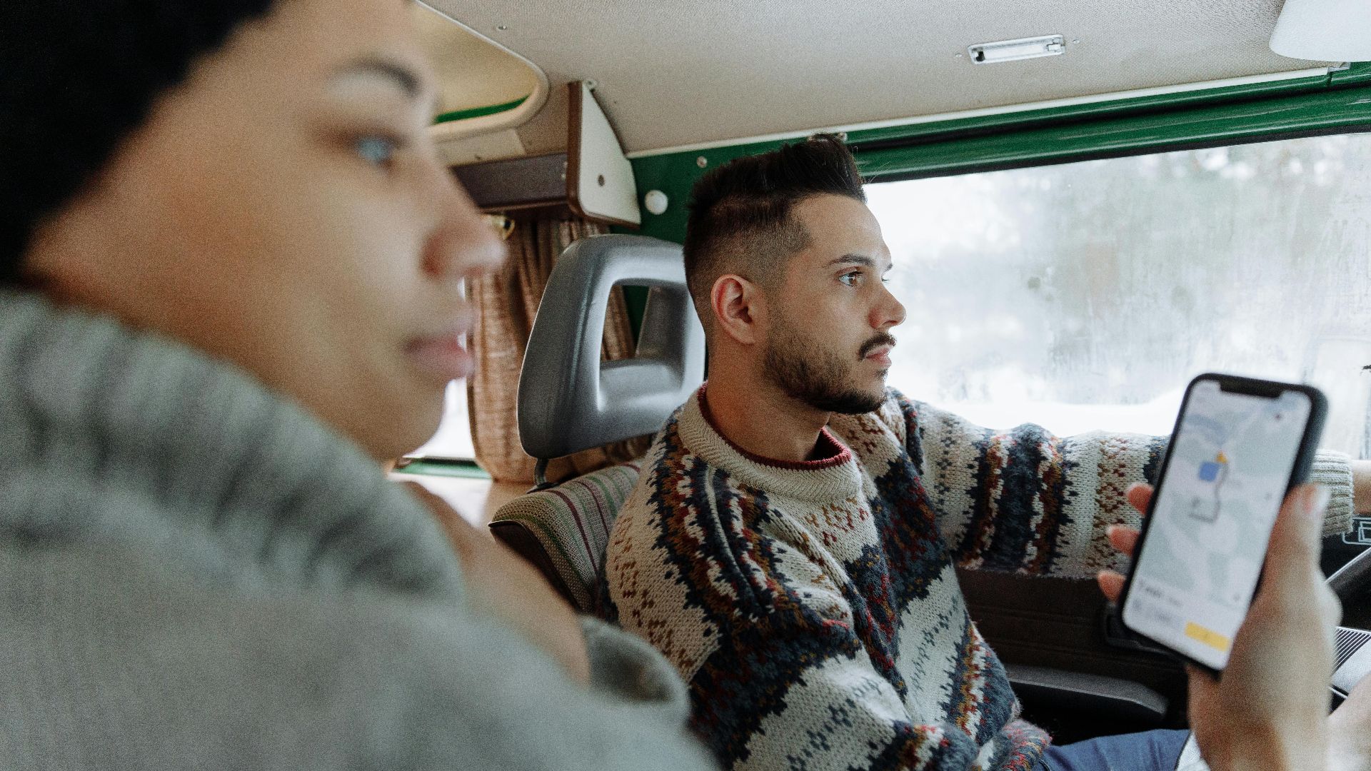 Couple using navigation app in a vintage campervan during a road trip.