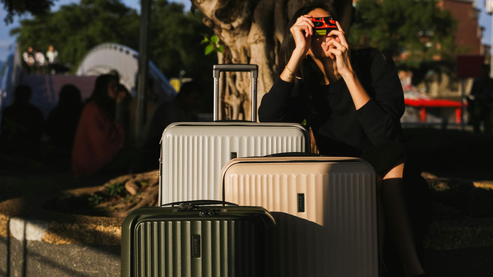 A woman captures moments with a vintage camera beside suitcases outdoors. Perfect for travel themes.
