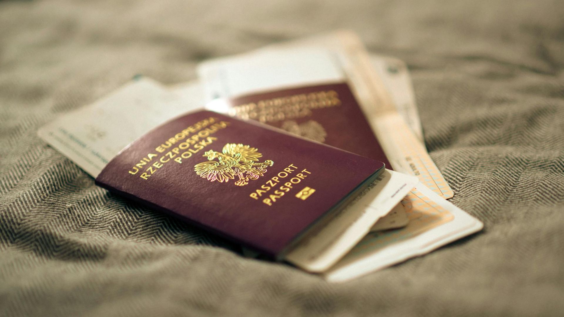 A close-up of a Polish passport and travel documents placed on a fabric surface, symbolizing travel and identity.