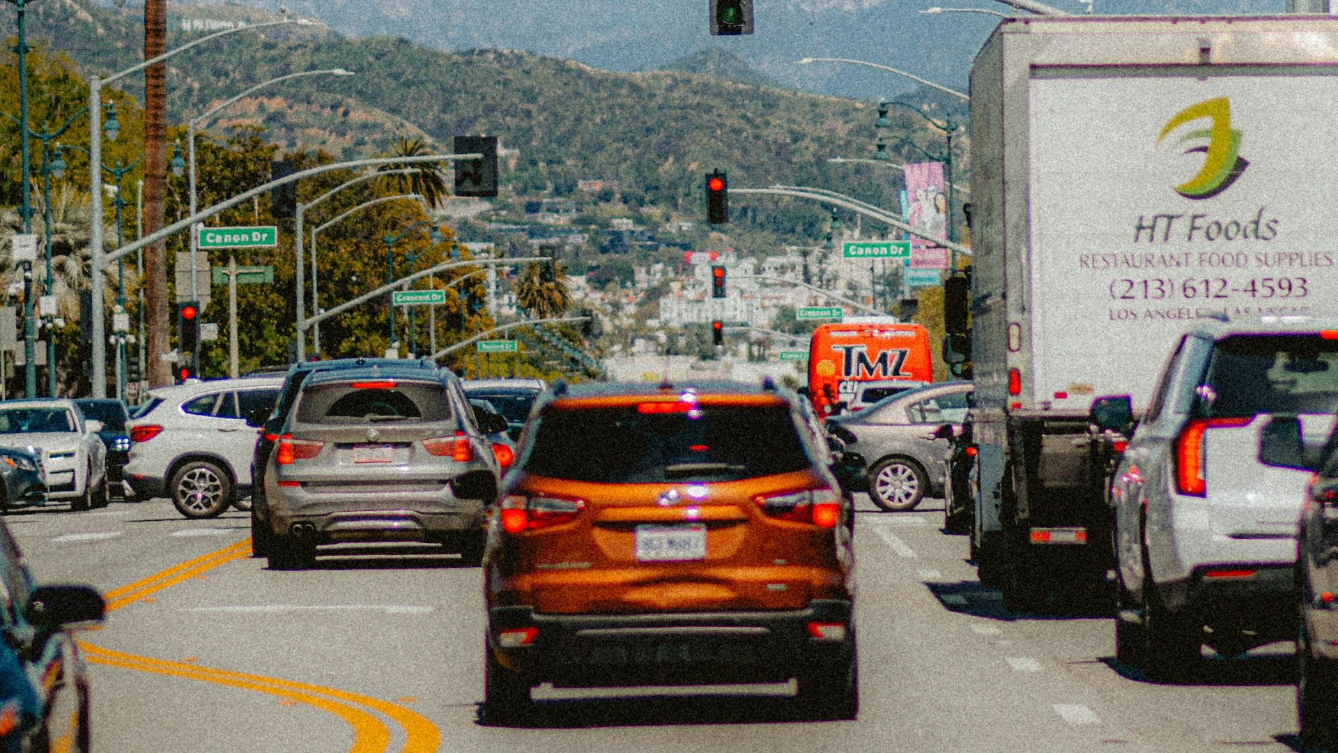 Urban traffic scene with cars and trucks under a clear sky, highlighting city life and transportation.