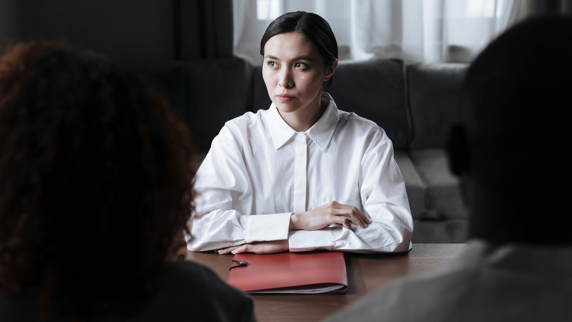 Business meeting with woman in a white shirt discussing documents with clients.