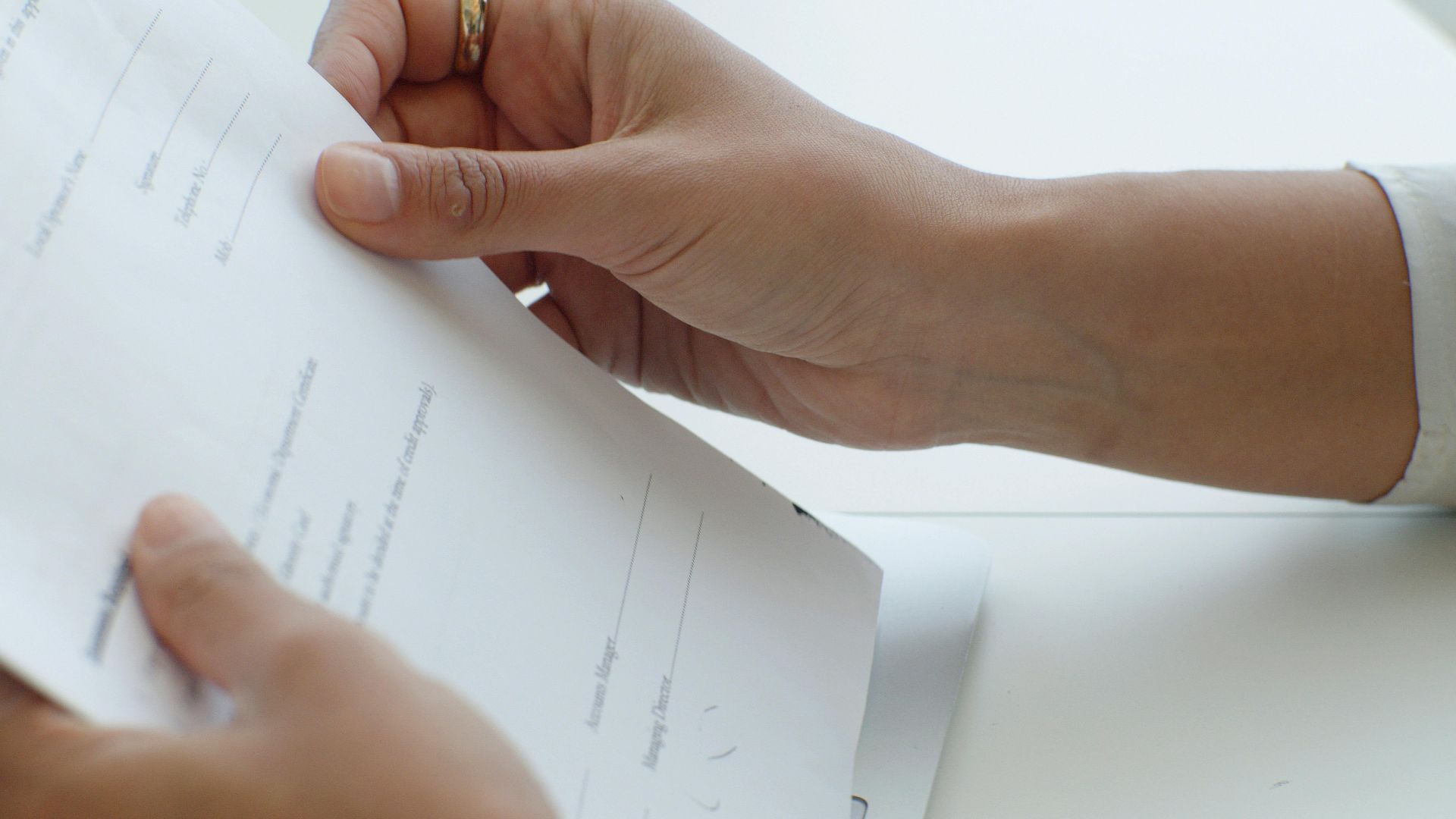 Close-up view of hands holding a document over a keyboard in an office.