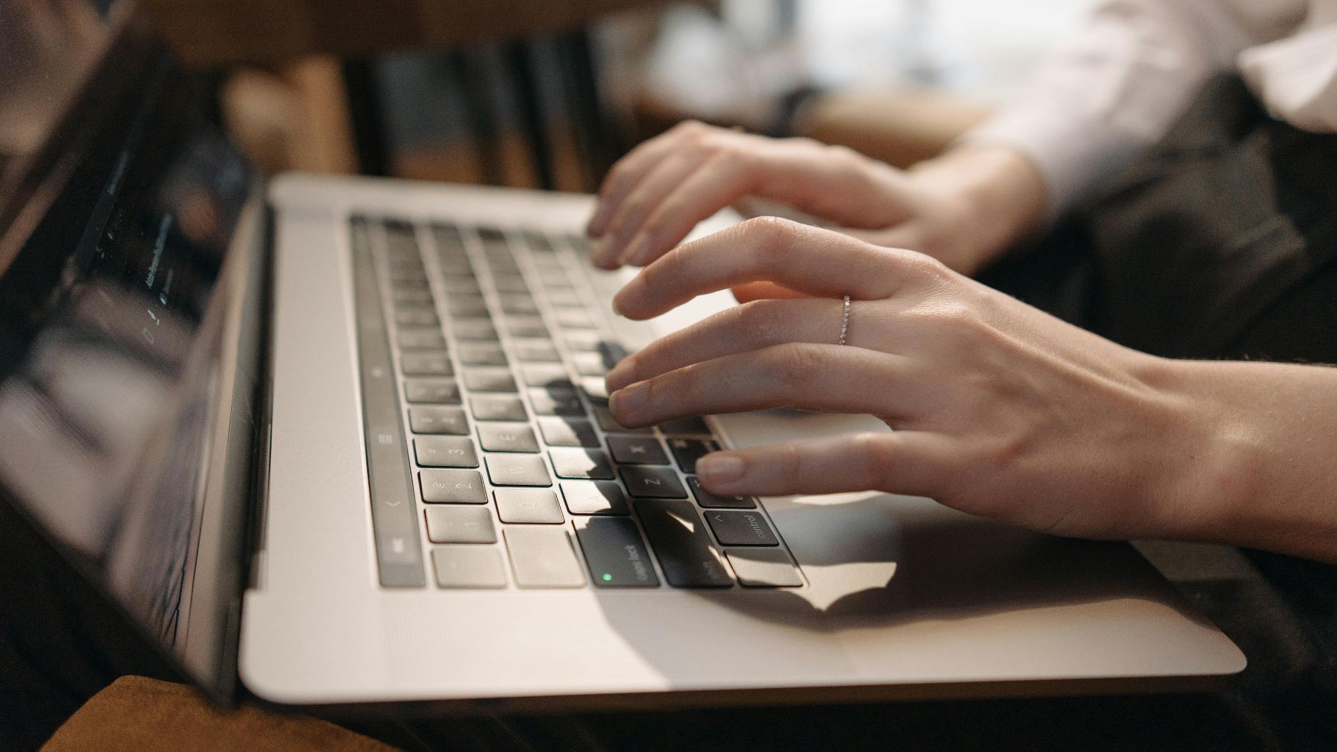 Close-up of hands typing on laptop in a cozy setting, ideal for remote work content.