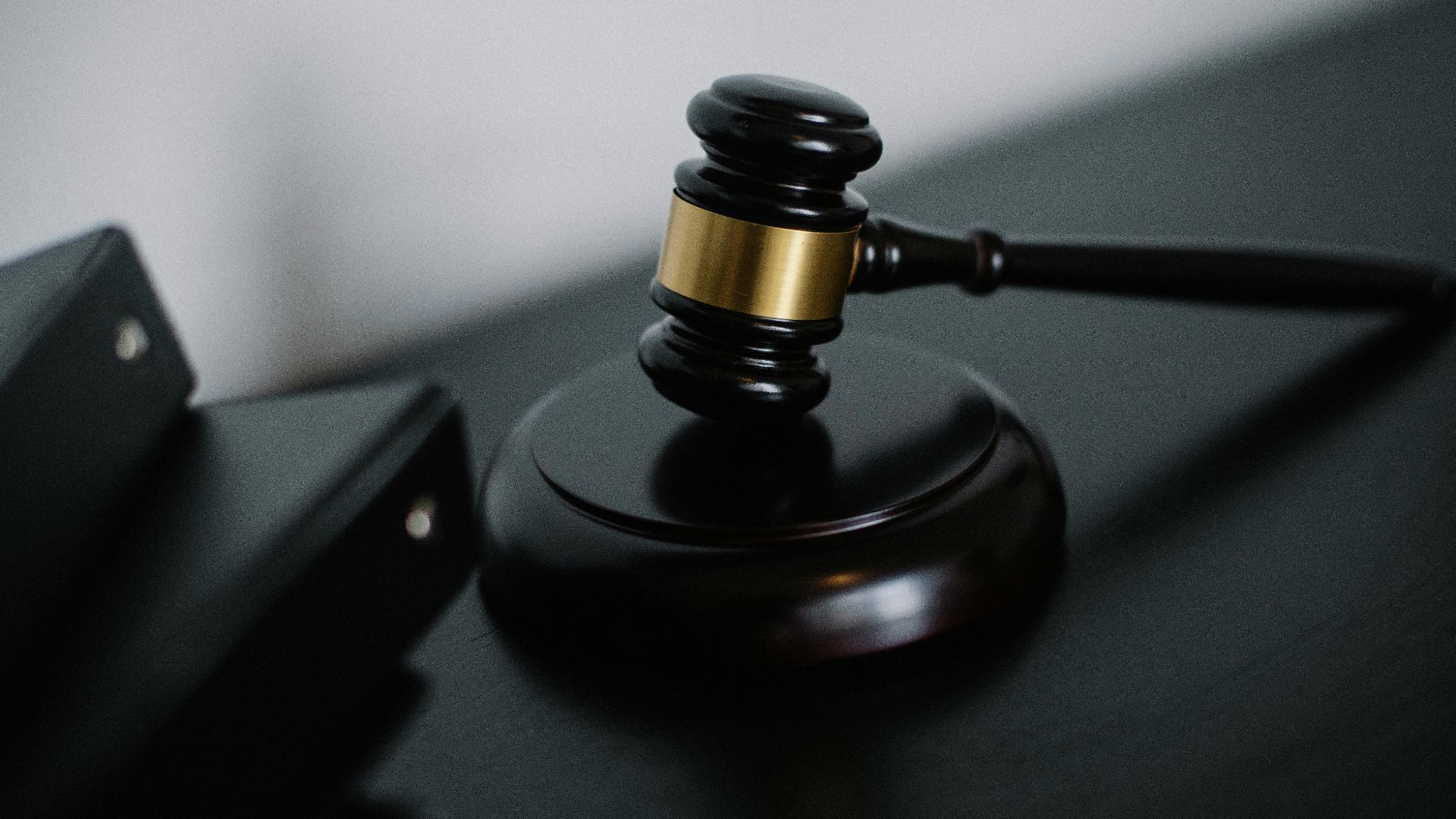 High angle of shiny wooden ceremonial mallet with golden detail placed on judge tale near documents folders
